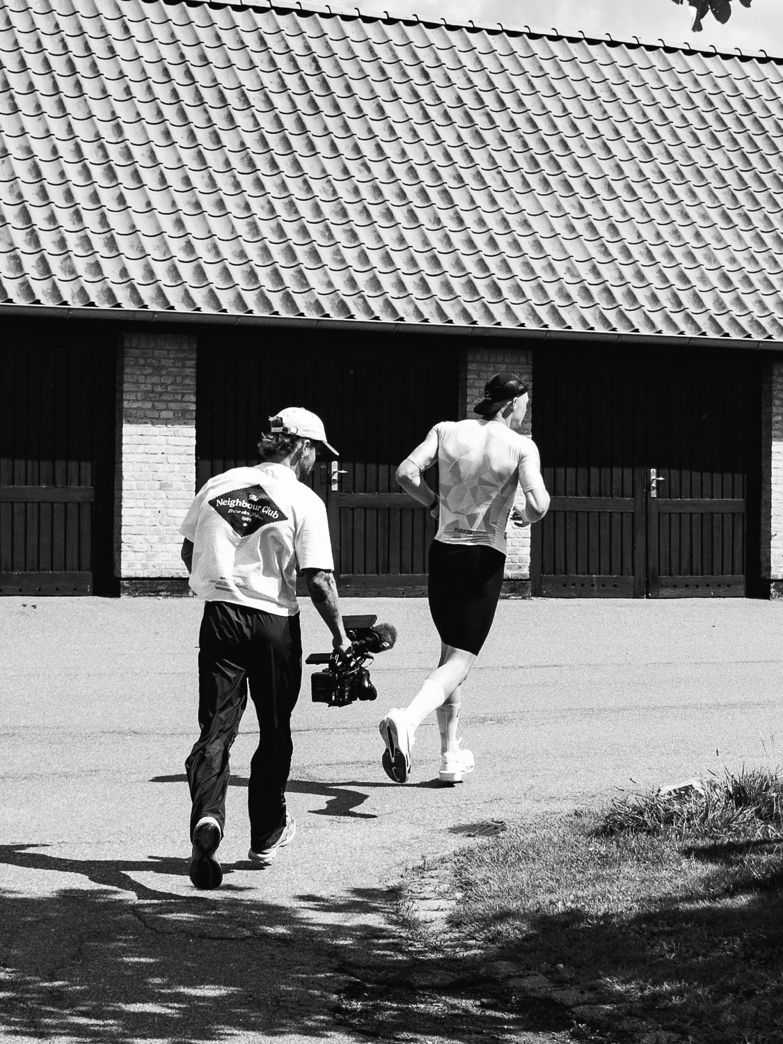 Filmmaker running behind a triathlete with a camera and microphone, black and white